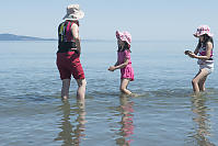 Kids Walking With Grandma In Shallow Bay