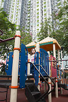 Nara On Climbing Frame In Shadow Of Tall Buildings